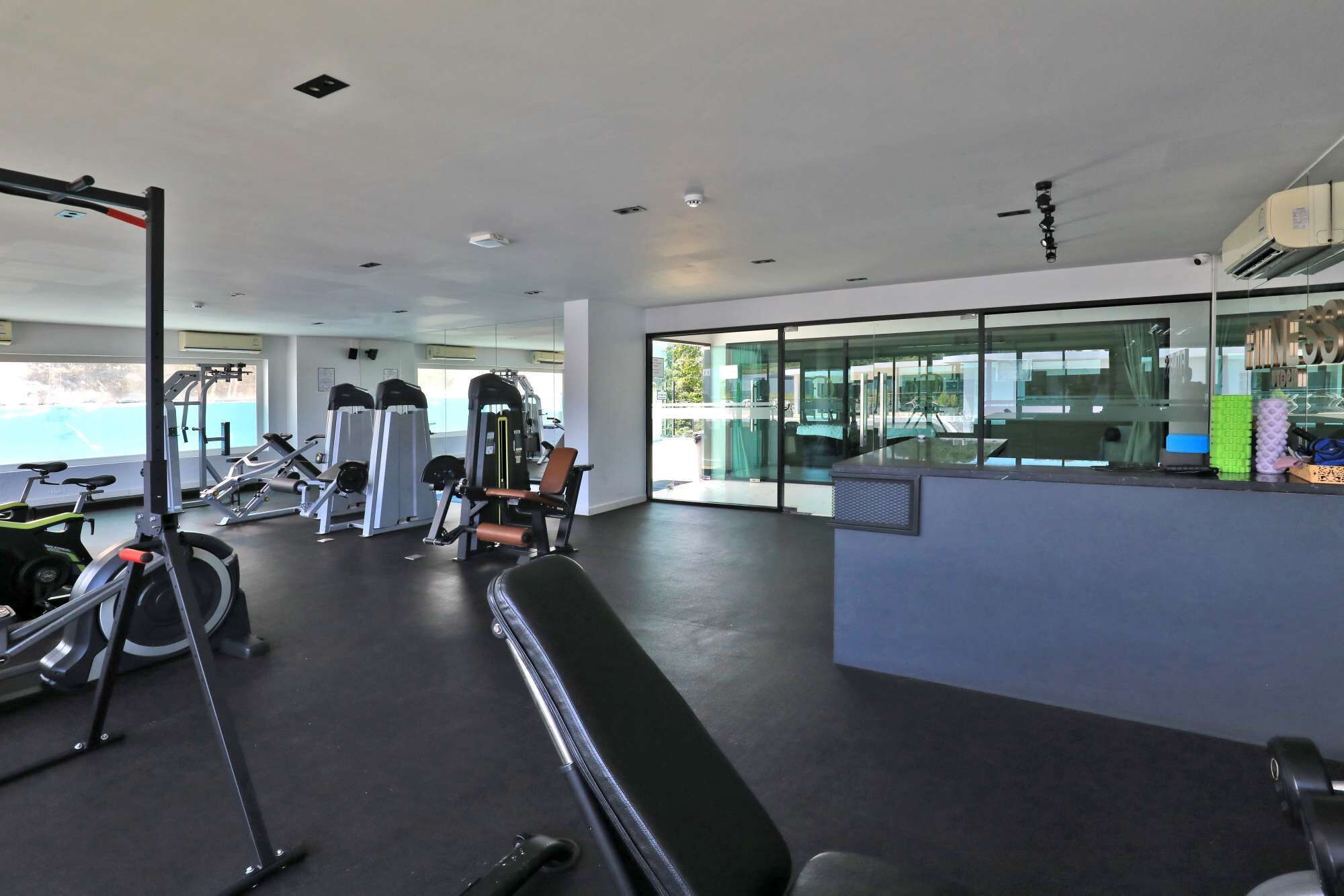 Un gimnasio con equipo de ejercicio, una banca y un amplio ventanal.
