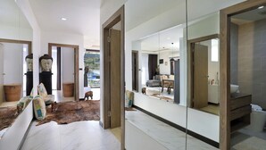 A modern interior with a large mirror, a wooden door, and a view of a dining area. - 2 bdr Apartment with bath NaiHarn Beach (Rawai)