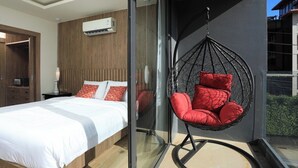 A modern bedroom with a bed, a hanging chair, and an air conditioning unit. - 2 bdr Apartment with bath NaiHarn Beach (Rawai)
