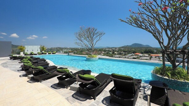 A poolside area with lounge chairs, a clear blue pool, and a view of the landscape. - 2 bdr Apartment with bath NaiHarn Beach (Rawai)