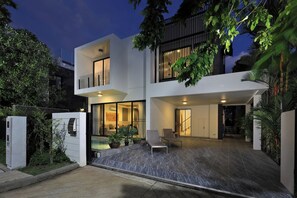 A modern two-story house with a swimming pool, outdoor seating, and a well-lit entrance. - Laguna Park | Bangtao Beach | 5-bedroom Pool Villa (Bangtao)
