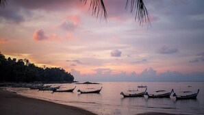 Une plage avec des bateaux et une mer calme au coucher du soleil.
