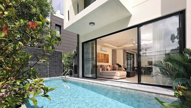 Une maison moderne dotée d’une piscine, d’une porte vitrée donnant sur un espace de vie et d’un mur en pierre.
