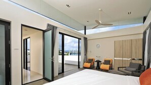 Une chambre d’hôtel moderne dotée d’un grand lit, d’un balcon avec des portes vitrées, d’un ventilateur de plafond et offrant une vue sur la ville.
