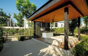 Ein moderner Außenbereich mit Terrassenmöbeln, einer Holz-Pergola und einem kleinen Wasserspiel.
