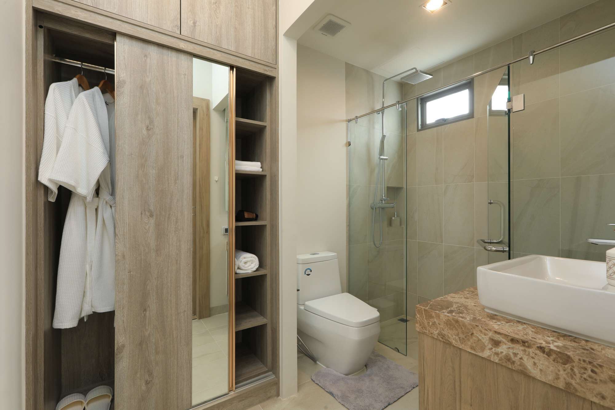 A modern bathroom with a glass shower enclosure, a white toilet, and a large sink.