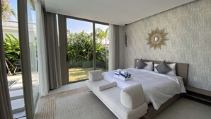 Quarto moderno com uma cama grande, um sofá-cama e vista para um jardim através de grandes portas deslizantes.