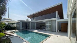 Uma casa moderna com piscina, portas de vidro e área de varanda.