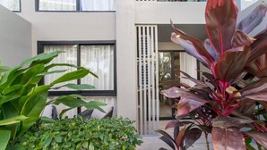 Ein modernes Gebäude mit großen Fenstern, einem Balkon und Zimmerpflanzen.