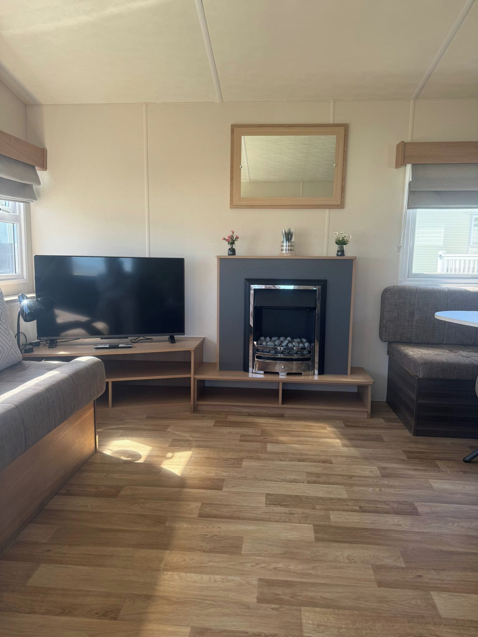 Uma sala de estar com televisão de tela plana, lareira, sofá e janela.
