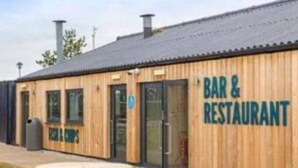 A wooden building with a sign reading 'BAR & RESTAURANT' and a picnic table outside. - Cabin Sleeps 4 With Wifi (Lossiemouth)