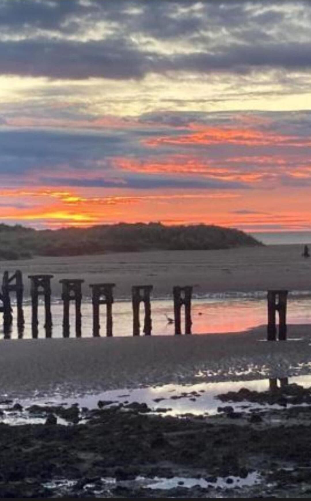 A sunset over a beach with wooden structures in the foreground.