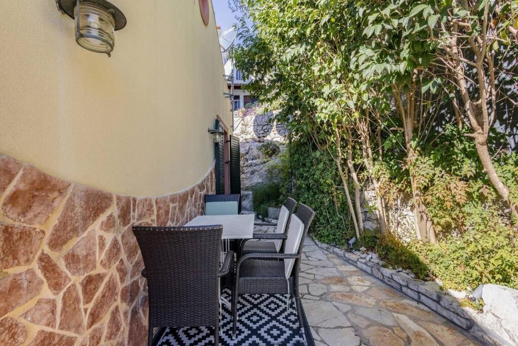 Un patio al aire libre con suelo de piedra, una mesa y sillas, y un aplique de pared.