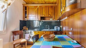 Eine Küche mit Holzausstattung, einer Arbeitsplatte aus Granit, einem Esstisch mit farbenfrohem Tischlein und einem Herd.