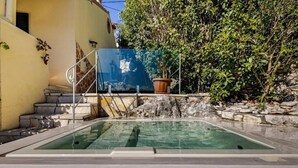 Ein Schwimmbecken mit einer Steinmauer und Stufen, die zu einem Gebäude führen.