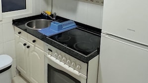 A kitchen with white cabinets, a black countertop, a stove, a sink, and a refrigerator. - Cozy Apartment in the Center of Avilés- Next to the Historic Center and Niemeyer (Avilés)