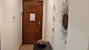 A hallway with a wooden door, a black table with bowls, and wall-mounted light fixtures. - Cozy Apartment in the Center of Avilés- Next to the Historic Center and Niemeyer (Avilés)