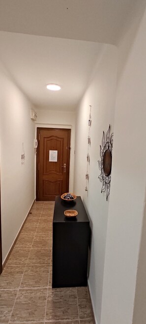 A hallway with a wooden door, a black table with bowls, and wall-mounted light fixtures.
