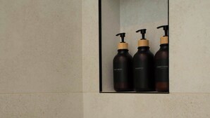 Un baño con cabina de ducha, un perchero y tres botellas de champú y acondicionador.
