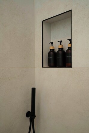 Ein Badezimmer mit Duschkabine, Handtuchhalter und drei Flaschen Shampoo und Conditioner.