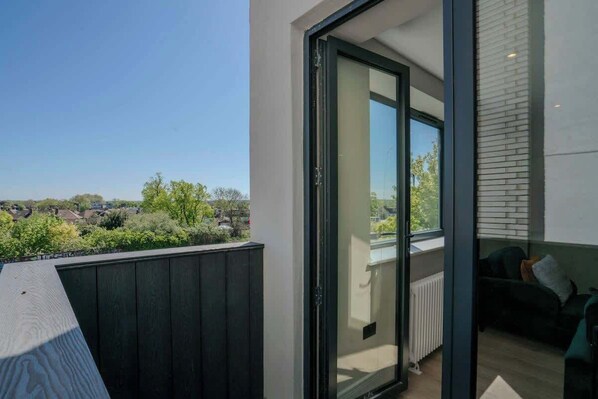 Ein modernes Apartment mit Balkon, Schiebeglastür und Blick auf eine Wohngegend.