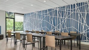 A conference room with a geometric patterned wall, multiple tables, and chairs. - Lower South End (Charlotte)