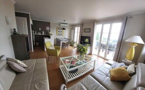 A modern living room with a sofa, coffee table, and a dining area with chairs. - Sea-view apartment with large terrace and pool in the heart of the Esterel region (Saint-Raphaël)