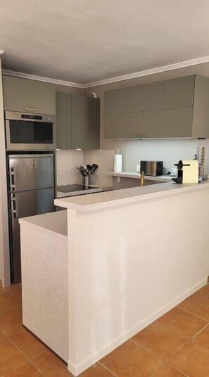 A modern kitchen with a central island, built-in appliances, and a neutral color palette. - Sea-view apartment with large terrace and pool in the heart of the Esterel region (Saint-Raphaël)