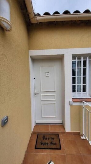 A white door with a number plate, a window with white frames, and a doormat with text. - Sea-view apartment with large terrace and pool in the heart of the Esterel region (Saint-Raphaël)