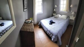 Une chambre à coucher avec un lit, des tables de chevet, un miroir et une fenêtre.
