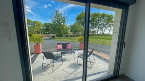 Una habitación con puerta corredera de cristal que da a un patio exterior con mesa y sillas.