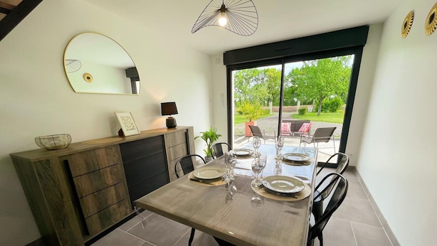 Un comedor con una mesa dispuesta para cuatro, un aparador de madera, un espejo y vistas al exterior.