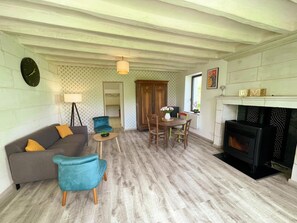 Ein Wohnzimmer mit einer Couch, Sesseln, einem Esstisch, einem Kamin und einer Uhr an der Wand.