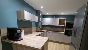 Une cuisine moderne avec des meubles de couleur bois clair, un îlot central intégré et des appareils électroménagers en acier inoxydable.