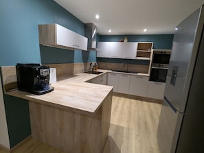 Une cuisine moderne dotée d’un îlot central, d’appareils électroménagers intégrés et d’une finition en bois clair.