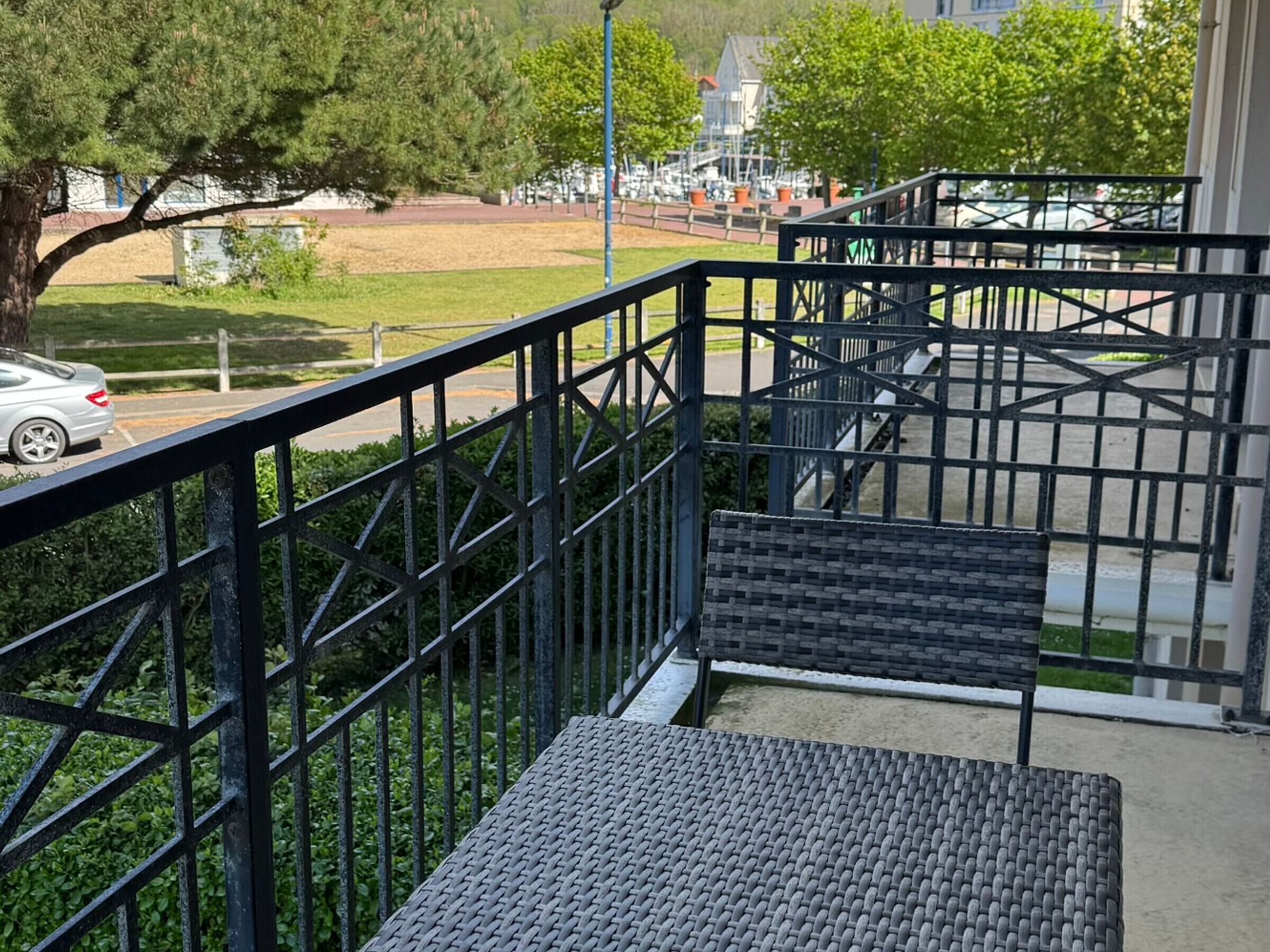 Un escalier avec des rampes en métal menant à un espace extérieur couvert où se trouve un banc.