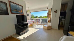 Un salón espacioso con televisión, una mesa de comedor y un balcón con vistas.