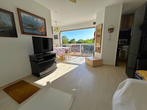 Ein geräumiger Wohnbereich mit Fernseher, Esstisch und Balkon mit Blick.