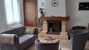 A living room with a sofa, armchair, fireplace, and a small table.