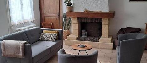 A living room with a sofa, armchair, fireplace, and a small table.