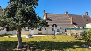 A house with a tiled roof, a fenced yard, and a large tree.