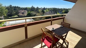 Un balcon avec une table et des chaises, une vue sur les maisons et un ciel dégagé.
