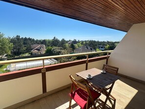 A balcony with a table and chairs, a view of houses, and a clear sky. - Duplex apartment with stunning sea view - 6 guests (Le Home Varaville)