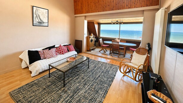 Un salon moderne avec un canapé, une table à manger et une vue sur la mer.