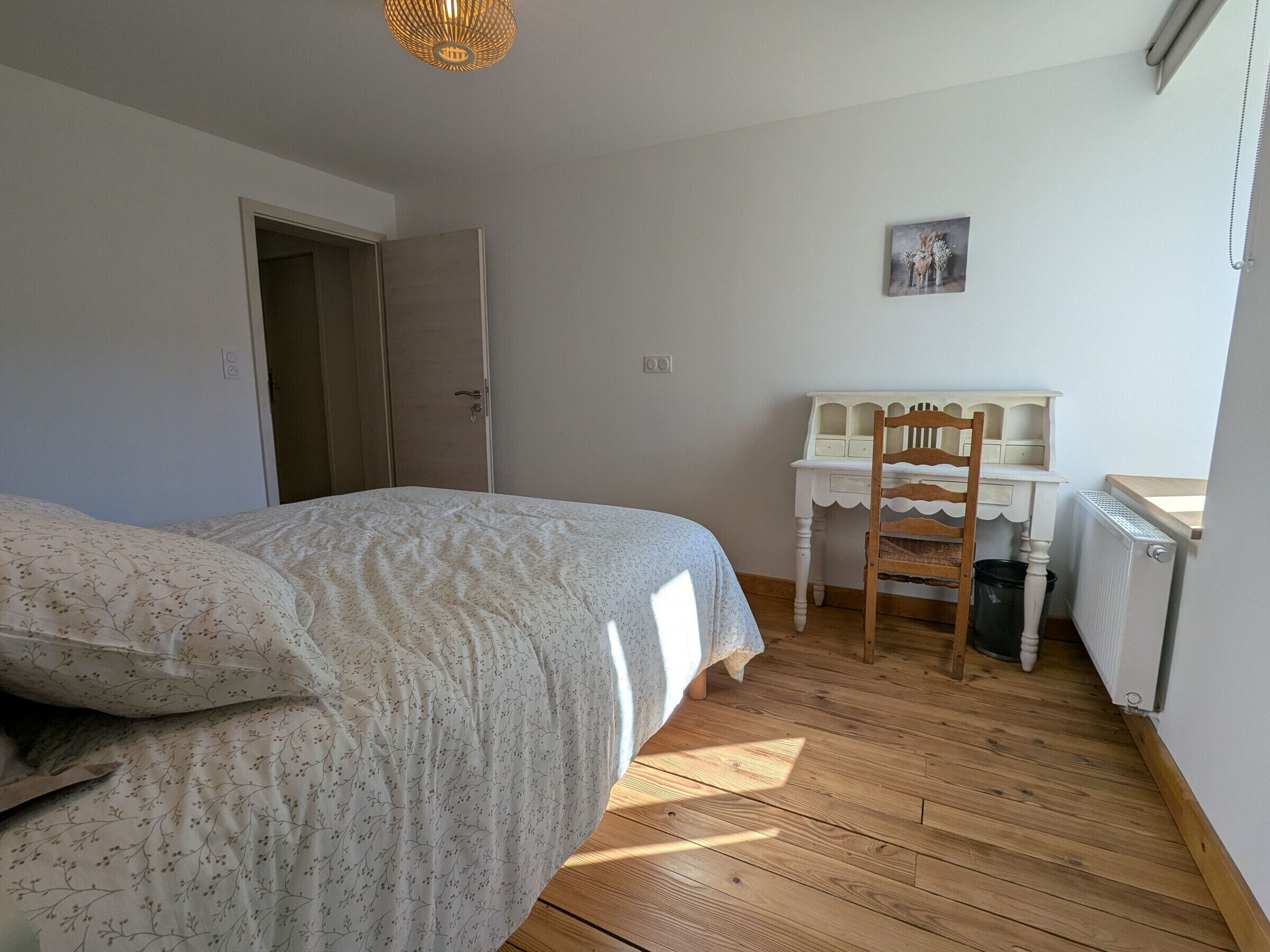 Een slaapkamer met een bed, een bureau, een stoel en een radiator.