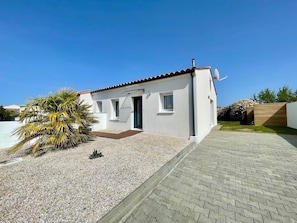A small, single-story building with a tiled roof, a gravel driveway, and a palm tree. - Recent house in quiet area - 4 guests (Bretignolles-sur-Mer)