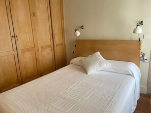 A bed with a wooden headboard, a white pillow, and a wall-mounted lamp. - Bright apartment Alhambra view - 4 guests (Granada)