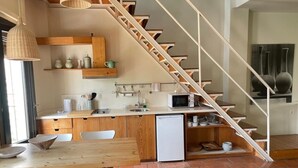 Een kleine keuken met een houten tafel, stoelen, een koelkast en een magnetron.