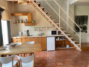 A compact kitchen with a wooden table, chairs, a refrigerator, and a microwave. - Bright apartment Alhambra view - 4 guests (Granada)