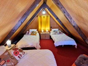 A cozy attic bedroom with two beds, a red carpet, wooden beams, and a yellow curtain. - Charming chalet, panoramic view - 5 guests (Saint-Michel-de-Chaillol)